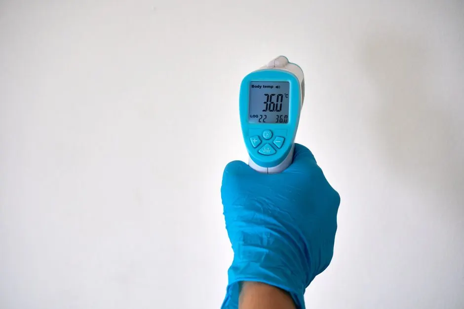 Gloved hand holding an infrared thermometer